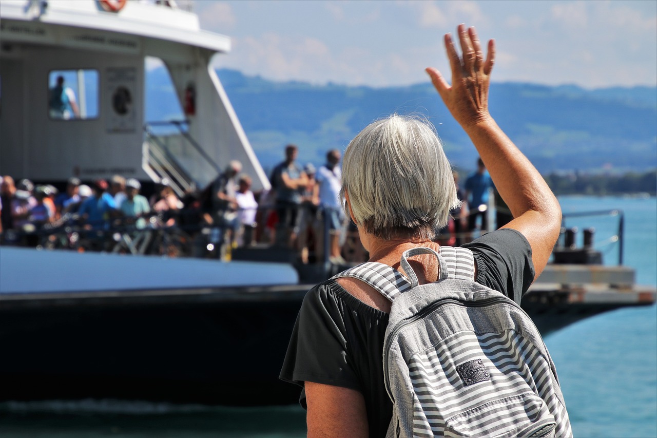 Senior happily waving at a departing ship, symbolizing the desire for stability and relief from Mal de Debarquement through effective treatment.